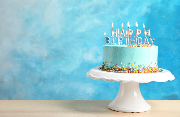 Fresh delicious birthday cake with candles on stand against color background. Space for text - Foto, afbeelding