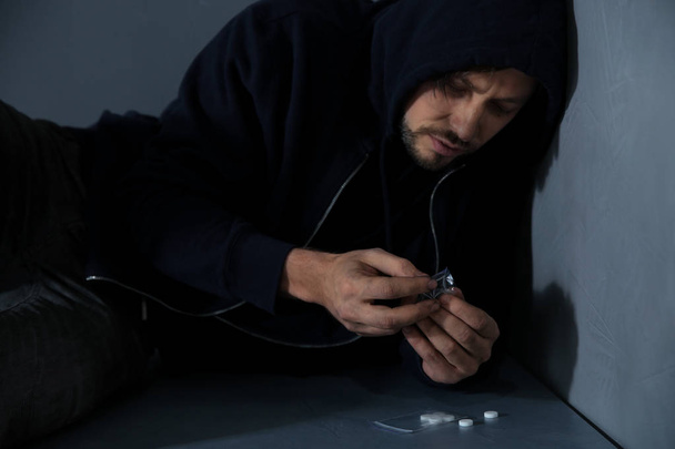 Молодий залежний чоловік з наркотиками лежить на підлозі
 - Фото, зображення