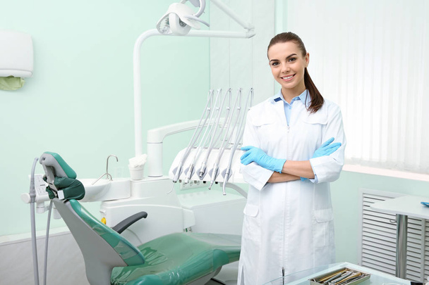 Young female dentist in white coat at workplace. Space for text - Fotoğraf, Görsel