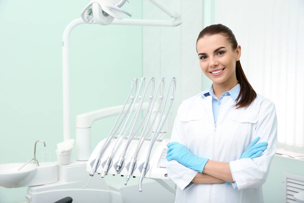 Young female dentist in white coat at workplace. Space for text - Fotografie, Obrázek