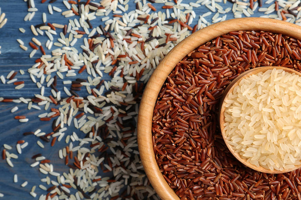 Flat lay composition with brown and other types of rice on color wooden background - Fotó, kép