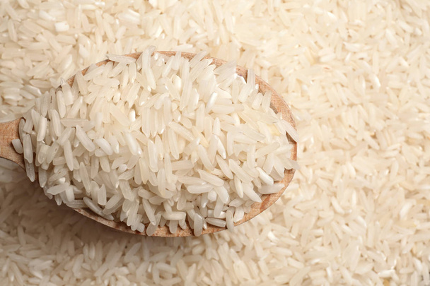 Long grain rice in wooden spoon, closeup view - Fotó, kép