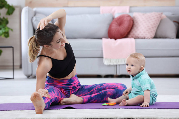 Young sportive woman doing exercise with her son at home. Fitness training - Фото, зображення