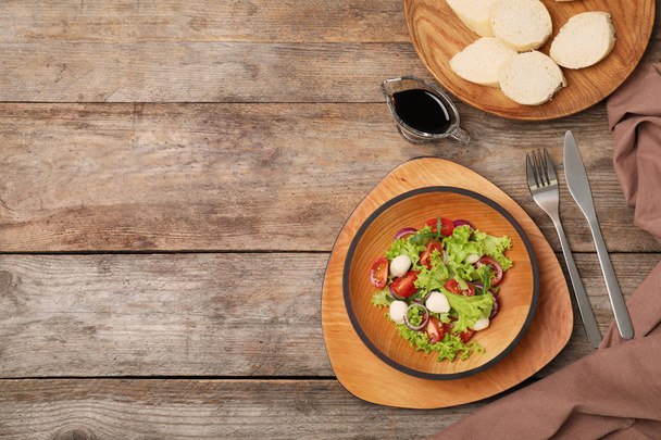 Flat lay composition with vegetable salad, balsamic vinegar and space for text on wooden background - Фото, зображення