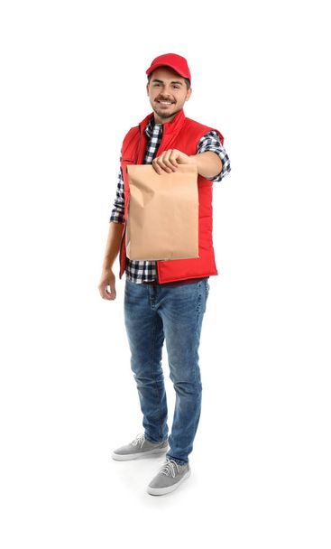 Young courier with paper bag on white background. Food delivery service - 写真・画像