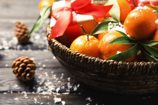 Bowl with ripe tangerines, Christmas gift and artificial snow on wooden table, closeup - Fotoğraf, Görsel