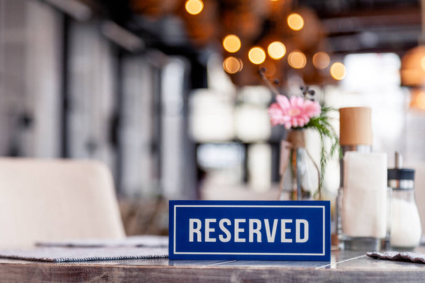 Closeup ξύλινα μπλε λευκό ορθογώνιο πιάτο με το στέκεται δεσμευμένη λέξη σε γκρι vintage τραπέζι στο εστιατόριο κοντά στη ρύθμιση, λευκό χαρτοπετσέτες, αλάτι πιπέρι σέικερ, μπολ ζάχαρη, βάζο με λουλούδια - Φωτογραφία, εικόνα