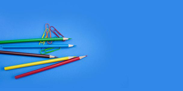 Web banner, poster wide template design concepts of stationery supplies, Colored crayon pencils and clips on blue background with copy space. Top view, Closeup. - Fotó, kép