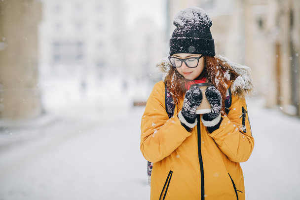 Woman Drinks Hot Tea or Coffee From a Cozy Cup on Snowy Winter Morning Outdoors - Photo, image