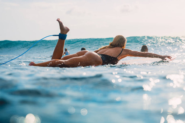June 22, 2018. Bali, Indonesia. Surf girl floating on surfboard. Woman in ocean during surfing. - Fotografie, Obrázek