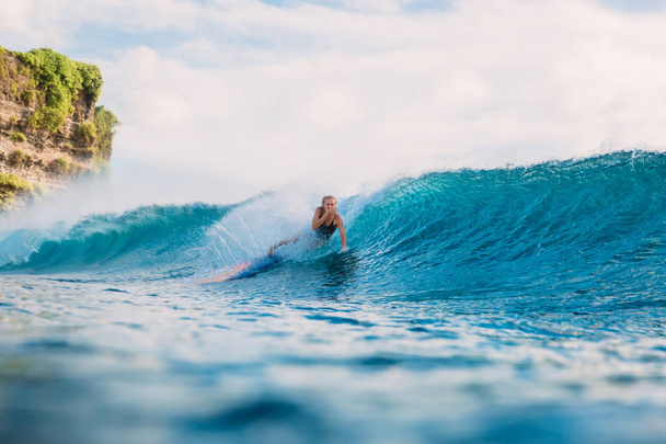Surf girl sulla tavola da surf. Spazzatura della donna surfista dalla tavola da surf sull'onda blu
 - Foto, immagini
