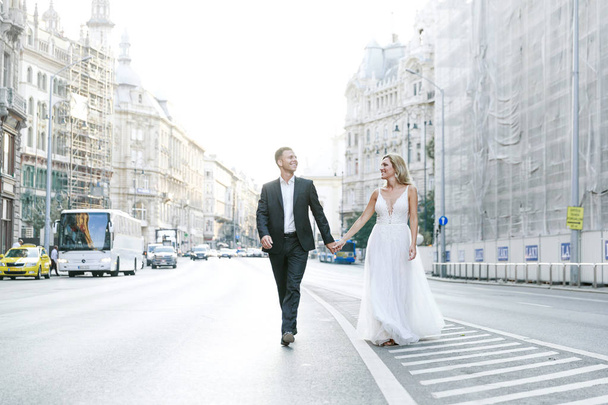 Bride and groom hugging in the old town street. Wedding couple in love. Luxury rhinestone dress. Hot summer days. - Foto, imagen