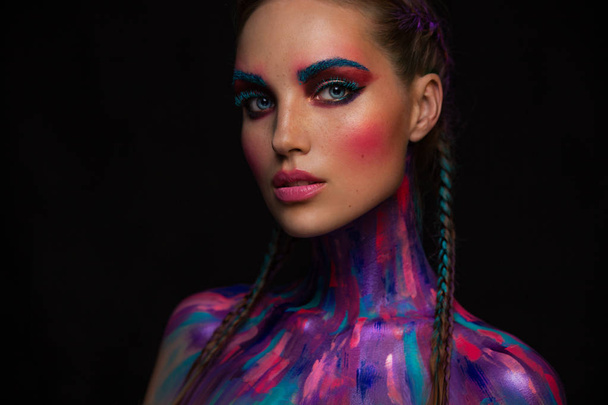 Fashion portrait of beautiful young woman with bright pink and blue colors, art make-up, face art on dark background - Foto, imagen