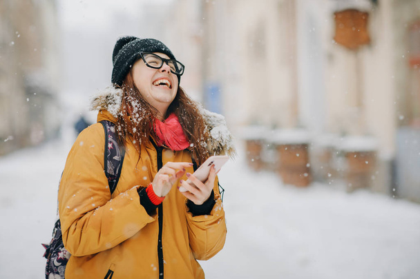 Portrait of teenage girl holding mobile phone outside in winter - Valokuva, kuva