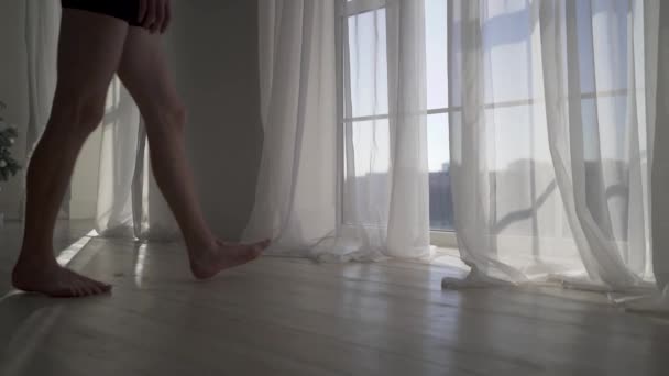 Naked man walking to window from floor to ceiling with white tulle. - Séquence, vidéo