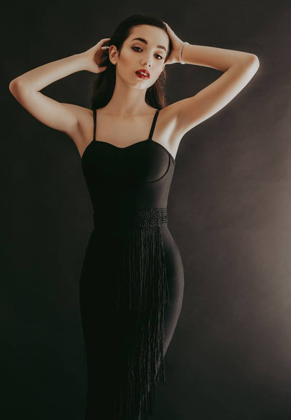 Красива молода жінка позує в чорній сукні в студії
 - Фото, зображення