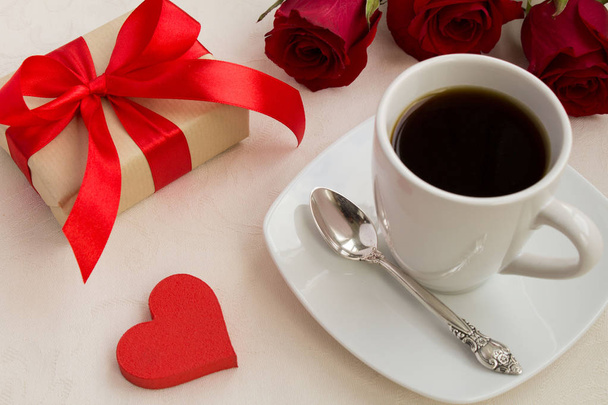 Coffee,gift and red roses on the beige tablecloth.View from above. - Photo, image
