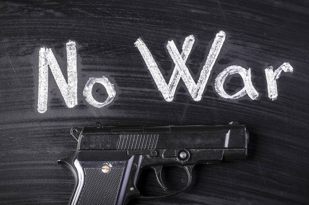 пистолет на доске рядом с надписью no war
 - Фото, изображение