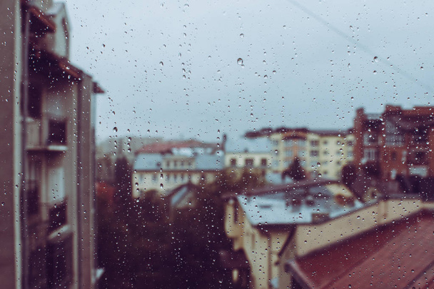 Belles gouttes de pluie en cristal sur le verre de la fenêtre. Bâtiments vus par la fenêtre. Après-midi d'automne nuageux. Des tons violets
 - Photo, image