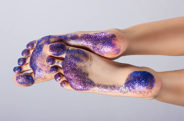 female feet closeup. They are raised and covered with colorful sequins. Traces. - Foto, Bild
