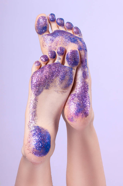 female feet closeup. They are raised and covered with colorful sequins. Traces. - Foto, Imagem
