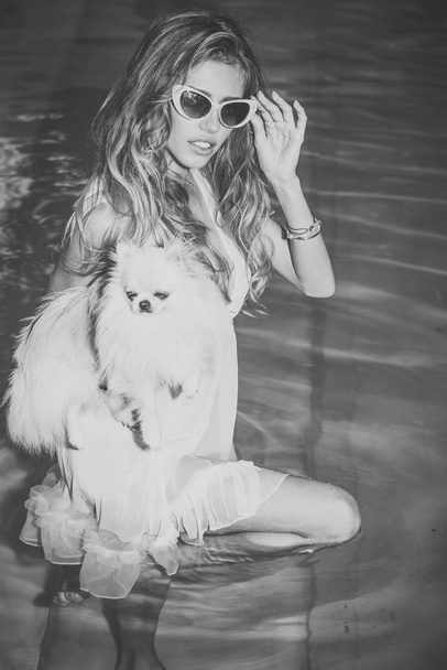 Sensual woman with cute spitz puppy in blue water - Photo, Image