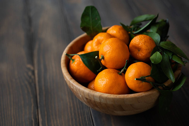 Tangerines - oranges, mandarines, clémentines, agrumes, avec des feuilles dans le panier sur fond en bois
 - Photo, image