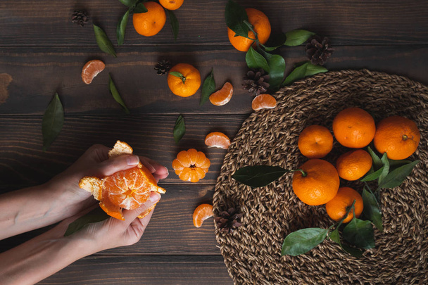 Manos femeninas sosteniendo mandarina sobre fondo de madera. Fondos de pantalla buenos para teléfono inteligente
 - Foto, imagen