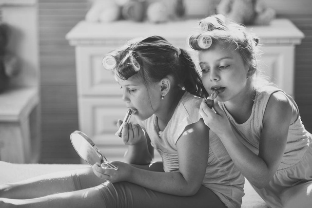 Kleine meisjes doen make-up zit in kamer met speelgoed - Foto, afbeelding