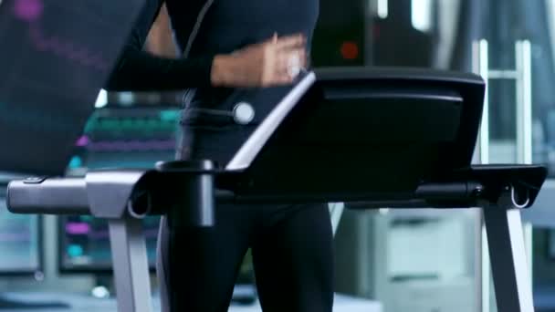 Beautiful Woman Athlete with Electrodes Connected to Her Body Runs on a Treadmill in a Sport Science Laboratory. In the Background High-Tech Laboratory with Monitors Showing EKG Readings. - Video, Çekim