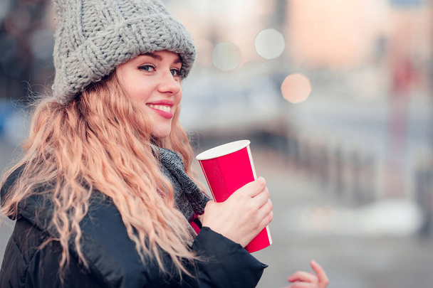 Woman Drink Her Hot Coffee While Walking On The Street. Portrait Of Stylish Smiling Woman In Winter Clothes Drinking Hot Coffee. Female Winter Style. - Image - Zdjęcie, obraz