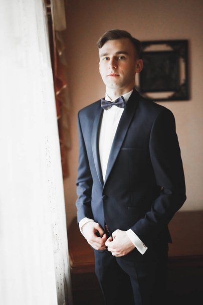 Grooms morning preparation. Handsome man getting dressed and preparing for the wedding - Фото, изображение