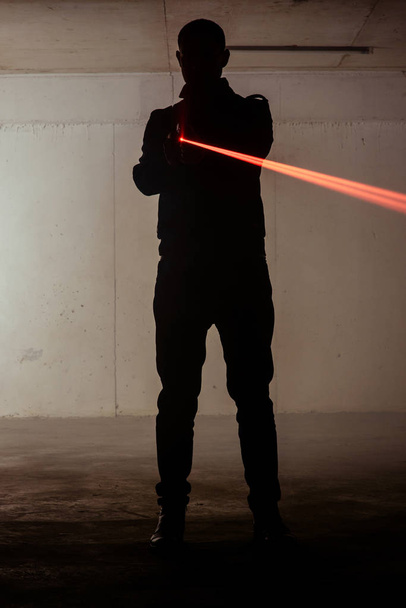 Shape of a assassin man who is holding laser gun in his hands - Photo, Image