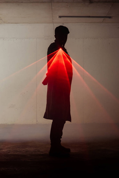 Silhueta de um homem que está em pé no quarto escuro e segurando arma com laser
 - Foto, Imagem