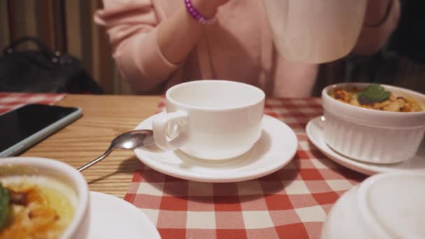 流行に敏感な女性の磁器のカップにお茶を注ぐ. - 映像、動画