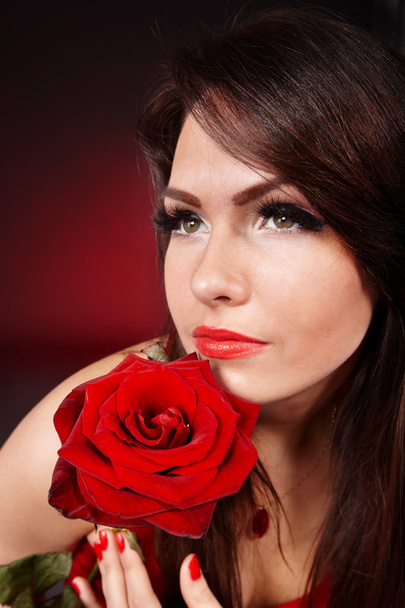 Girl with rose on red background. - Foto, afbeelding