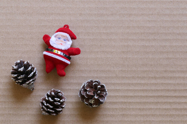 Santa panenky a šišky na hnědý tvrdý papír vánoční konceptu s kopií prostor pro design v práci. - Fotografie, Obrázek