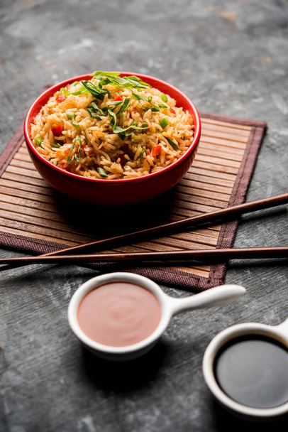 Schezwan Fried Rice Masala is a popular indo-chinese food served in a plate or bowl with chopsticks. selective focus - Foto, afbeelding