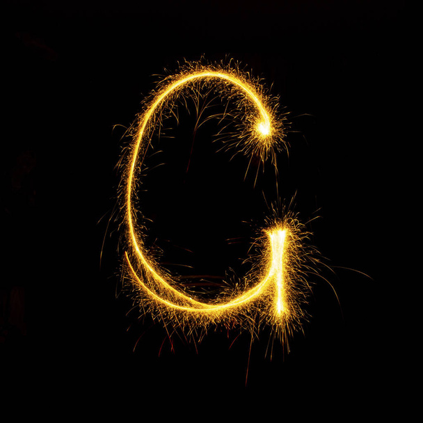 Alphabet sparklers on black background single letter - Foto, Imagen