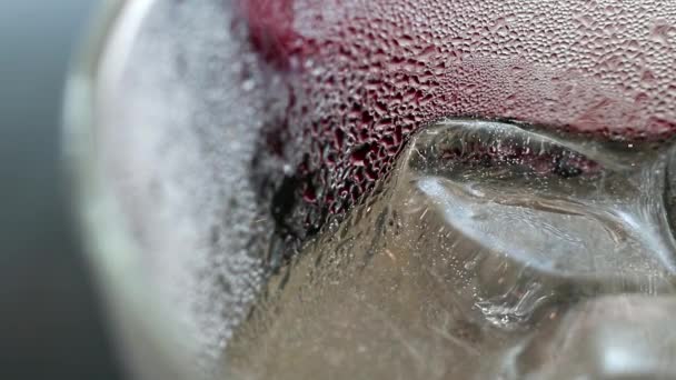 Beauté abstraite dans les détails des boissons. Extrême gros plan de boisson gazeuse glacée au jus de prune dans un verre. gouttes d'eau sur la surface du verre crée de beaux motifs de texture
. - Séquence, vidéo