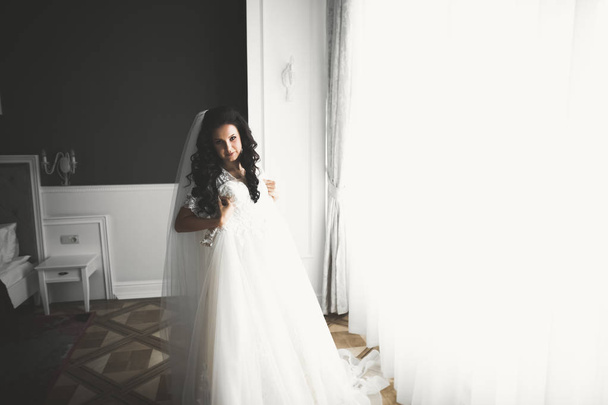 Gorgeous bride in robe posing and preparing for the wedding ceremony face in a room - Foto, imagen