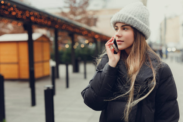 Pretty girl wear black, using phone with head phones, outdoor. Copy space - Фото, зображення