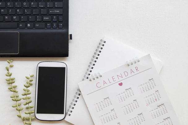 Планировщик ноутбуков, мобильный телефон, календарь, компьютер для работы в офисе стол на заднем плане белый
  - Фото, изображение