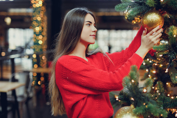 Pretty girl wear red, enjoing her time indoor Christmas place with lights. Copy space - Foto, Imagem