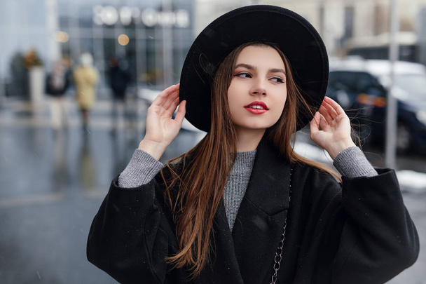 Young fashion woman walking on the city street wear black hat look around and smile to camera. Copy space. - Image - Photo, image