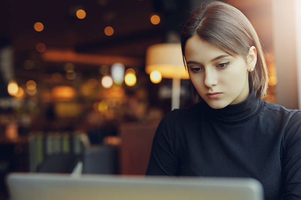 Kobieta rozejrzeć i uśmiech podczas pracy w Cafe na swojego laptopa. Portret stylowy uśmiechający się kobiety w zimowe ubrania Pracujesz w laptopie. Kobiece Bussiness stylu z Sun. - obraz - Zdjęcie, obraz