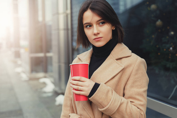 Woman Drink Her Hot Coffee While Walking On The Street. Portrait Of Stylish Smiling Woman In Winter Clothes Drinking Hot Coffee. Female Winter Style. - Image - Foto, Imagen