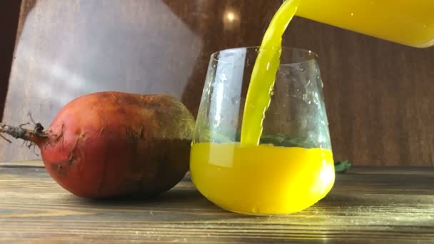 Κίτρινο τεύτλων χυμός σε ποτήρι στο τραπέζι - Πλάνα, βίντεο