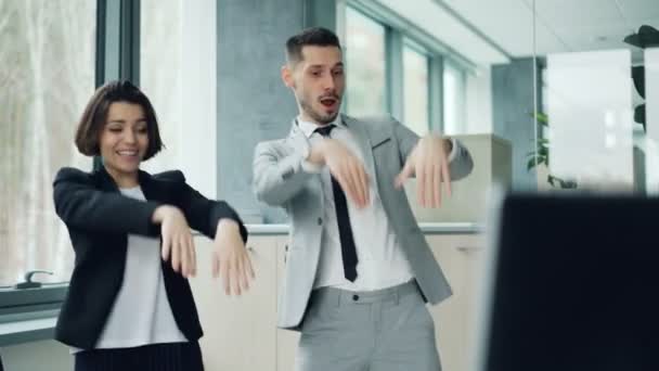 Careless office workers are relaxing at work dancing and laughing having fun together moving arms and bodies. Good mood, happy youth and workplace concept. - Filmmaterial, Video