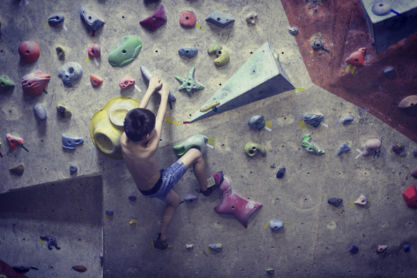 Little boy climbing a rock wall indoor. - Photo, Image